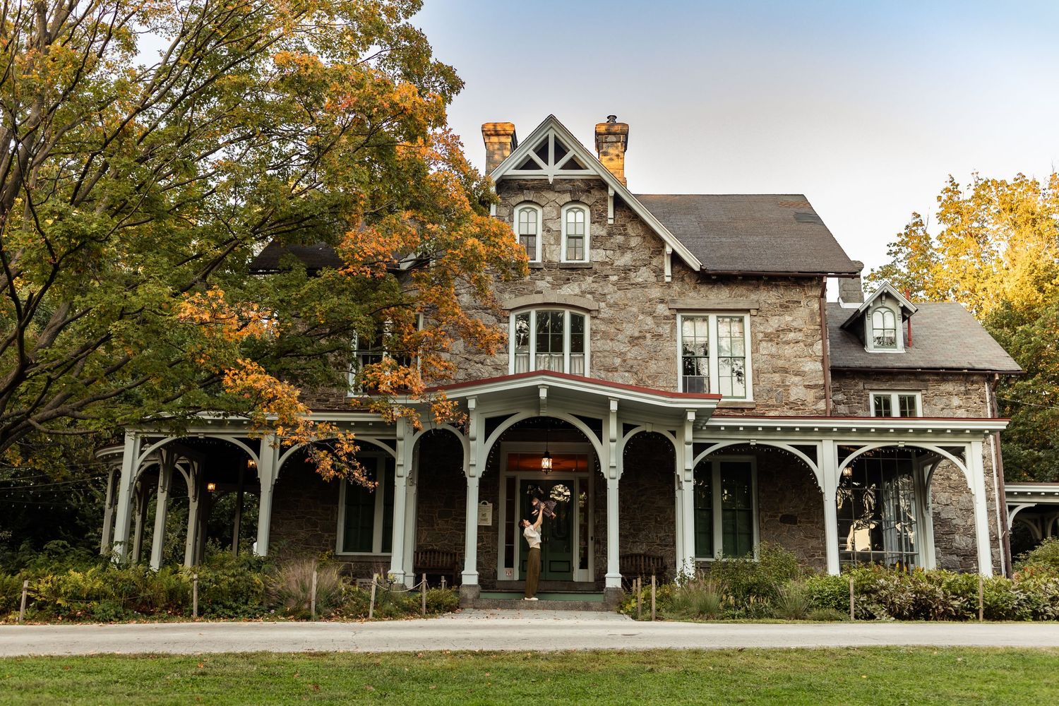 A mom playfully lifts up her baby in the entryway of a large stone house
