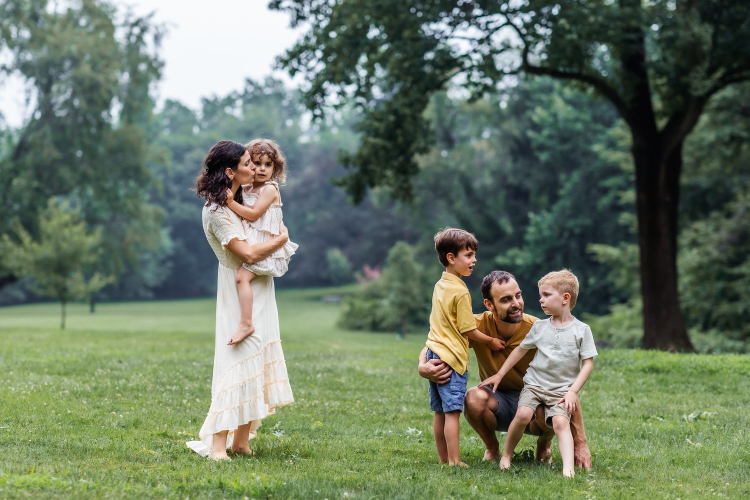 A family with three young kids quietly relax in an open green field