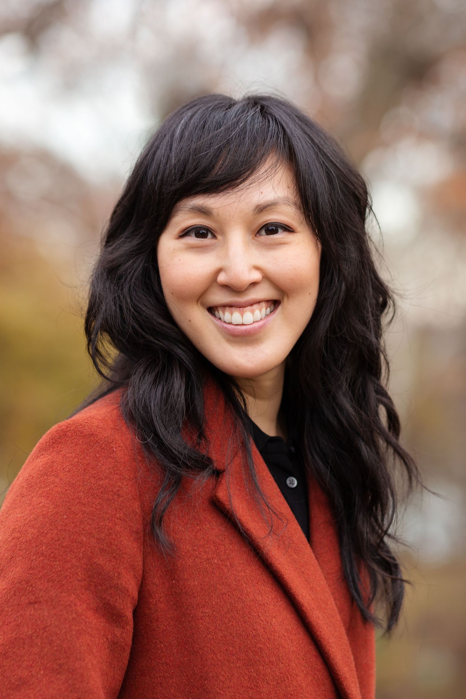 Outdoor portrait series showing natural smiles while wearing a rusty orange coat.