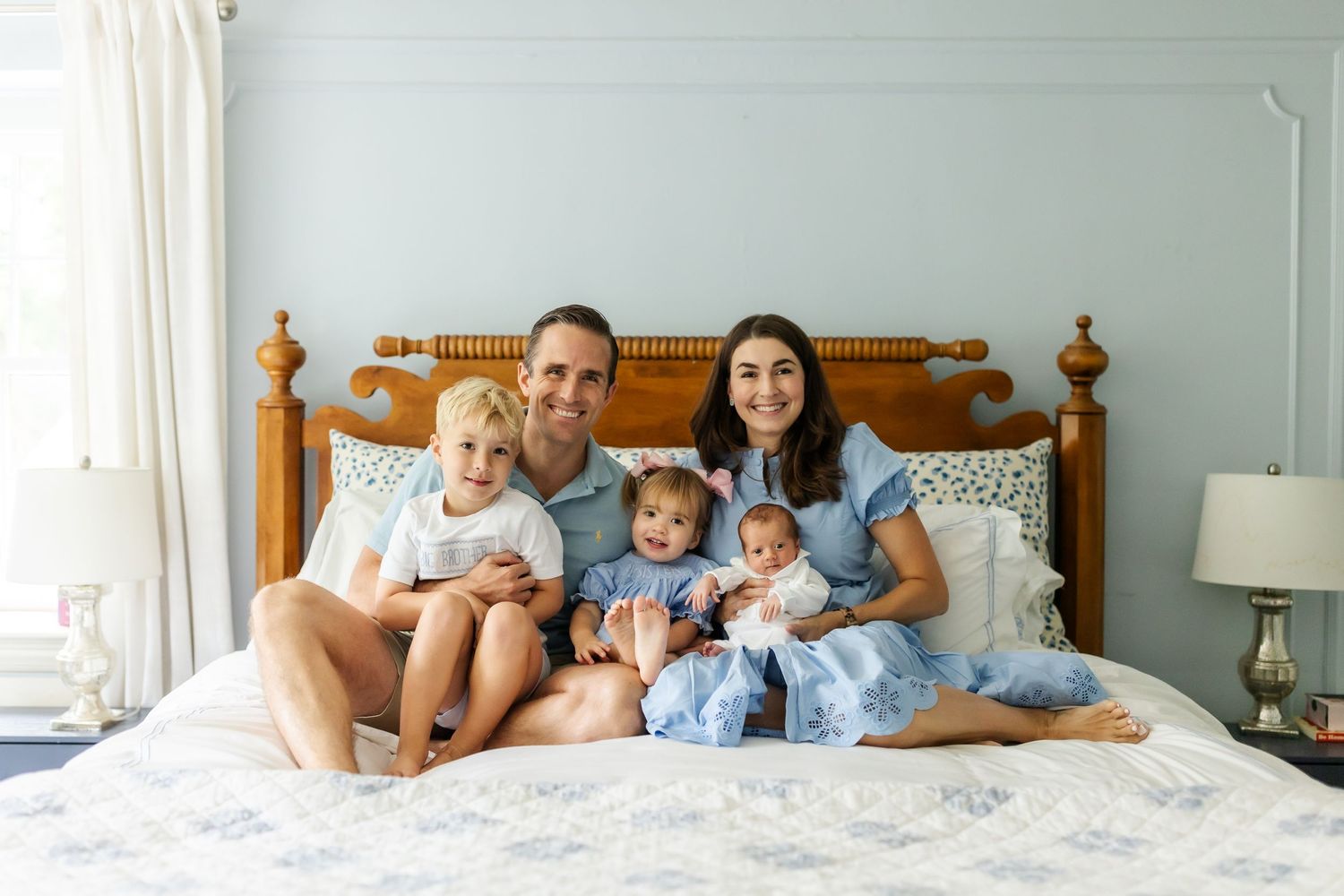 A family relaxing together on a wooden bed in a bright blue bedroom.
