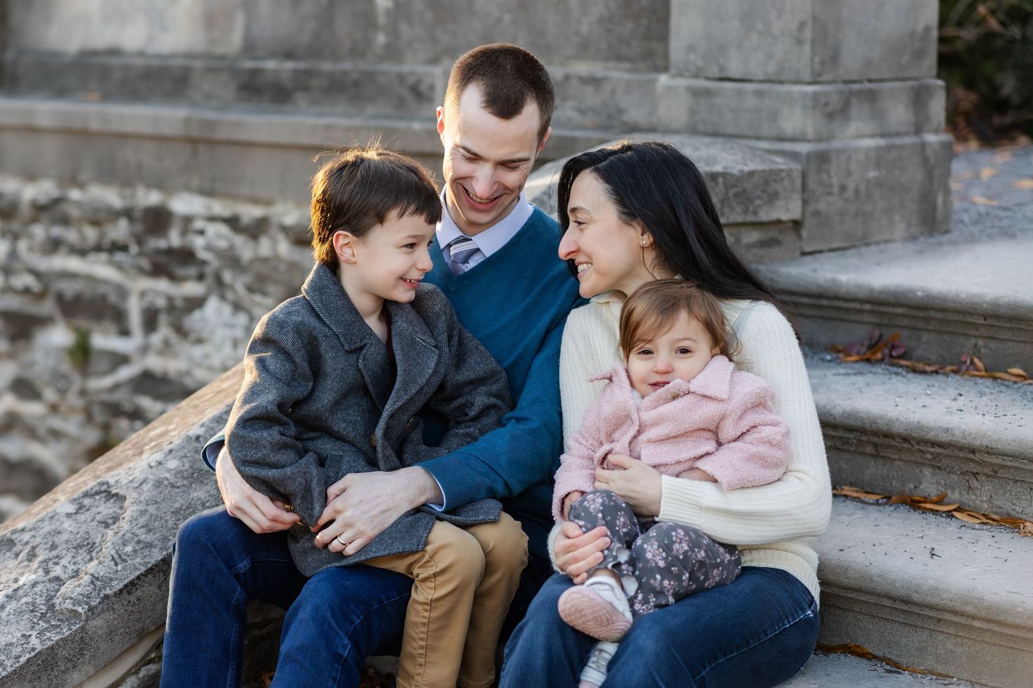 Family sharing an intimate moment while sitting on stone steps outdoors.