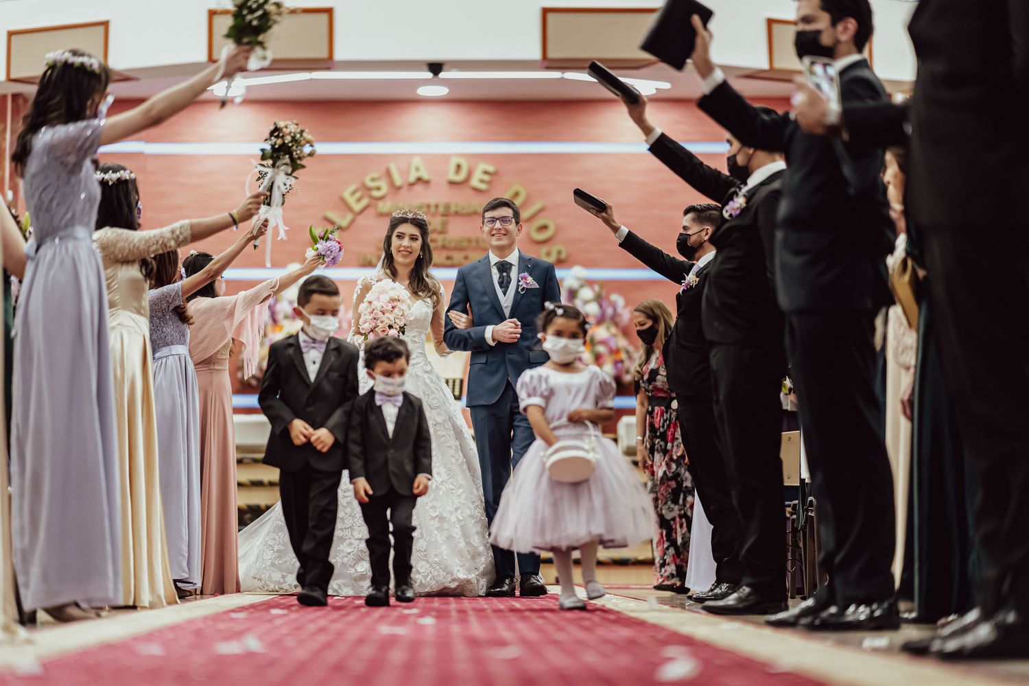 Pareja de esposo caminando junto a los pajesitos por el altar en una boda IDMJI