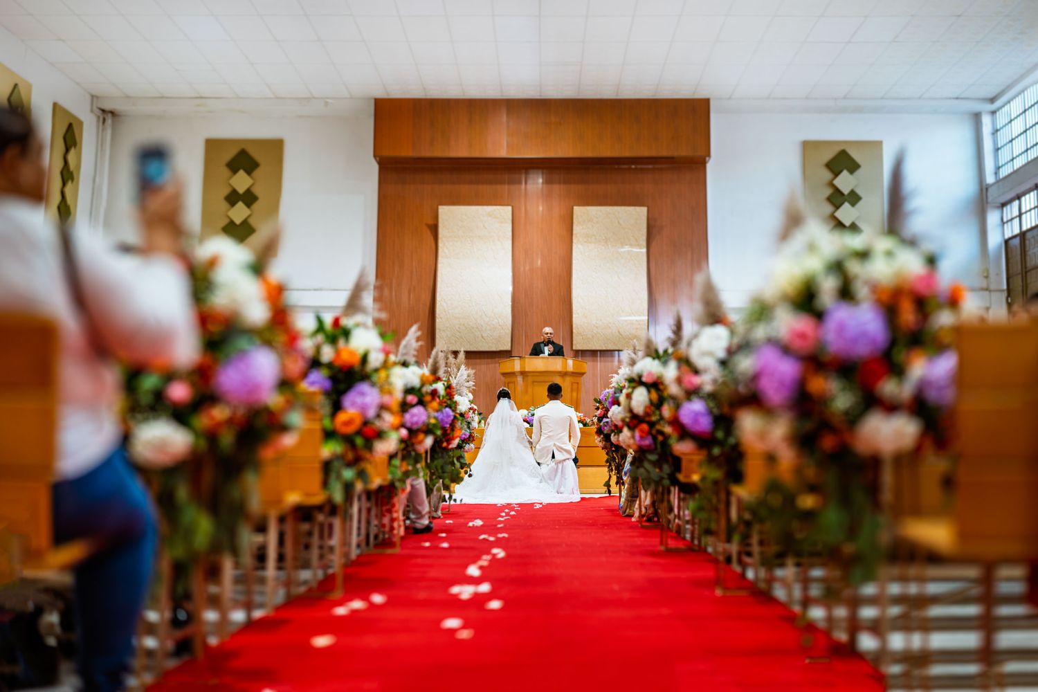 Pasillo de la iglesia decorado con flores y alfombra roja para la ceremonia de boda