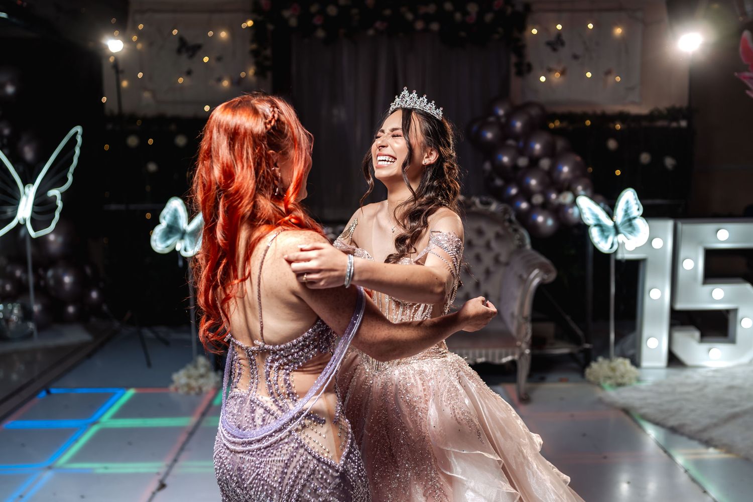 Quinceañera feliz baila con su madre pelirroja en fiesta de 15; pista iluminada, decoración mariposas neón.
