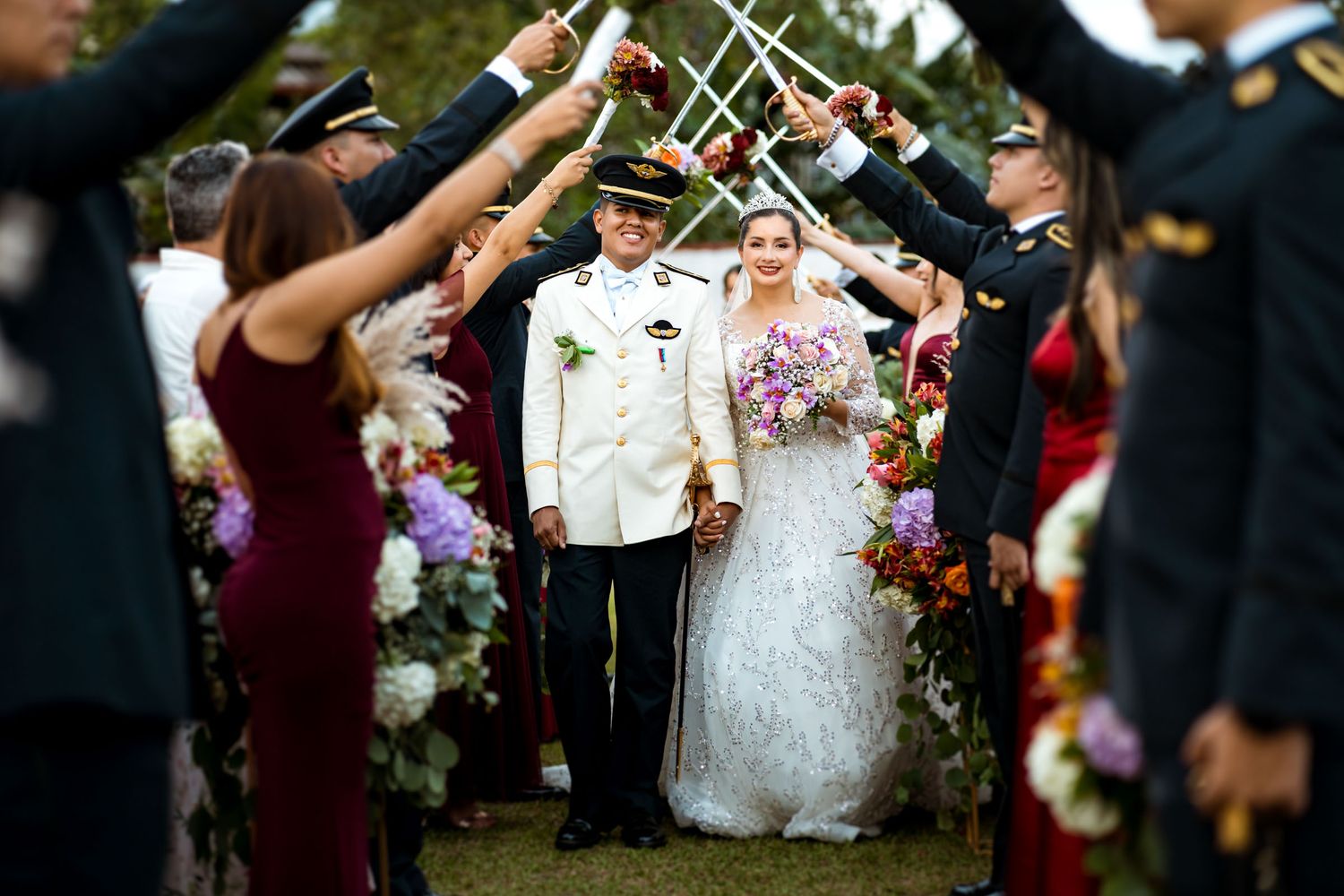 Novios recién casados caminan bajo el tradicional puente de acero en su boda militar en Villavicencio.