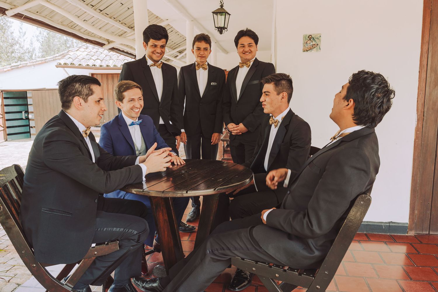 Novio y padrinos conversando y riendo sentados en una mesa.