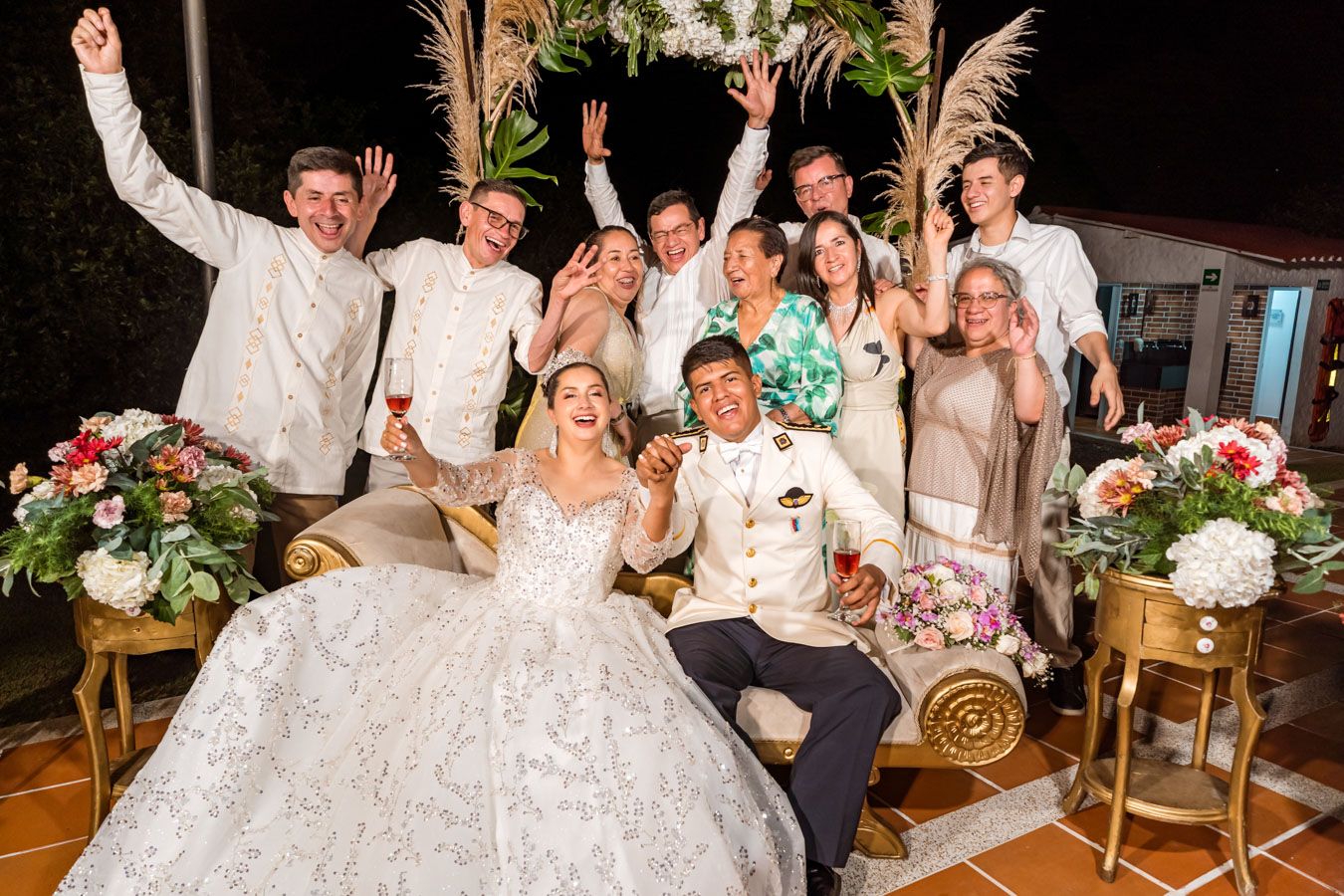 Novios y sus invitados celebran con los brazos en alto durante su boda