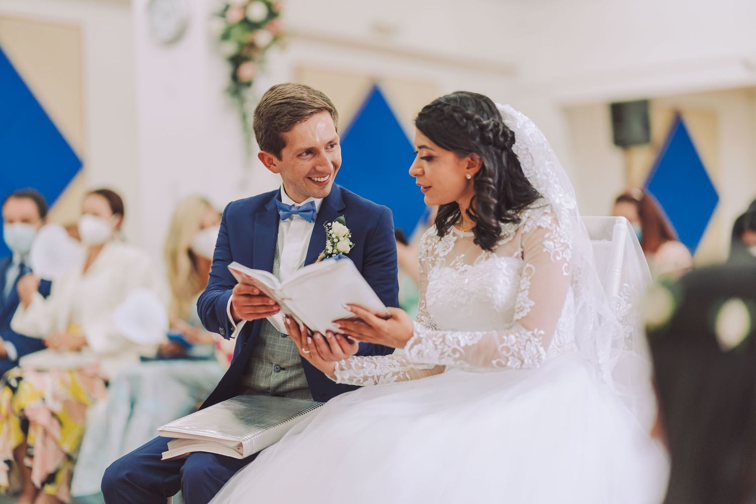 Novios sentados leyendo juntos el programa de su ceremonia de boda.