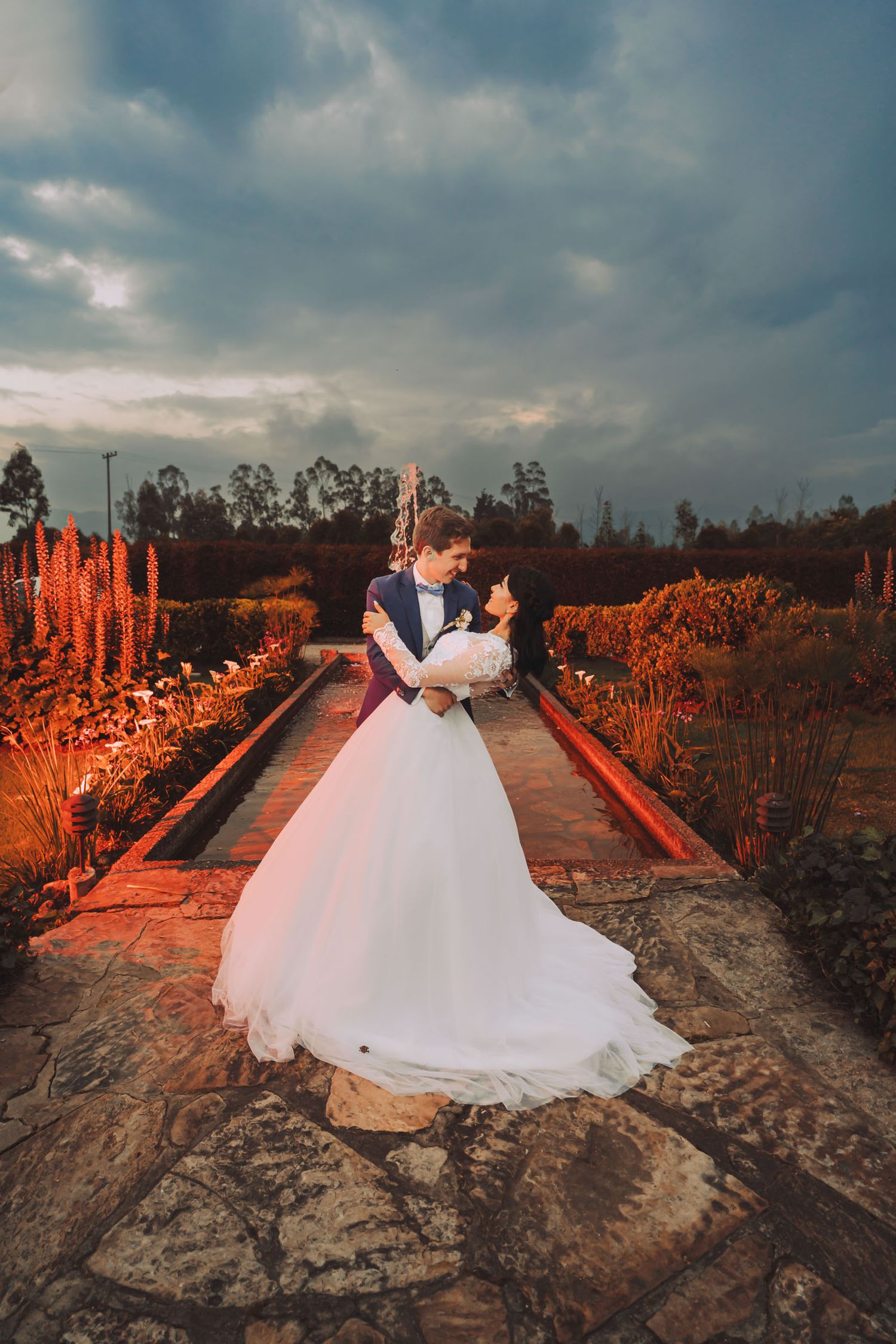 Novios abrazados en un puente rústico al atardecer en hacienda en Cajicá