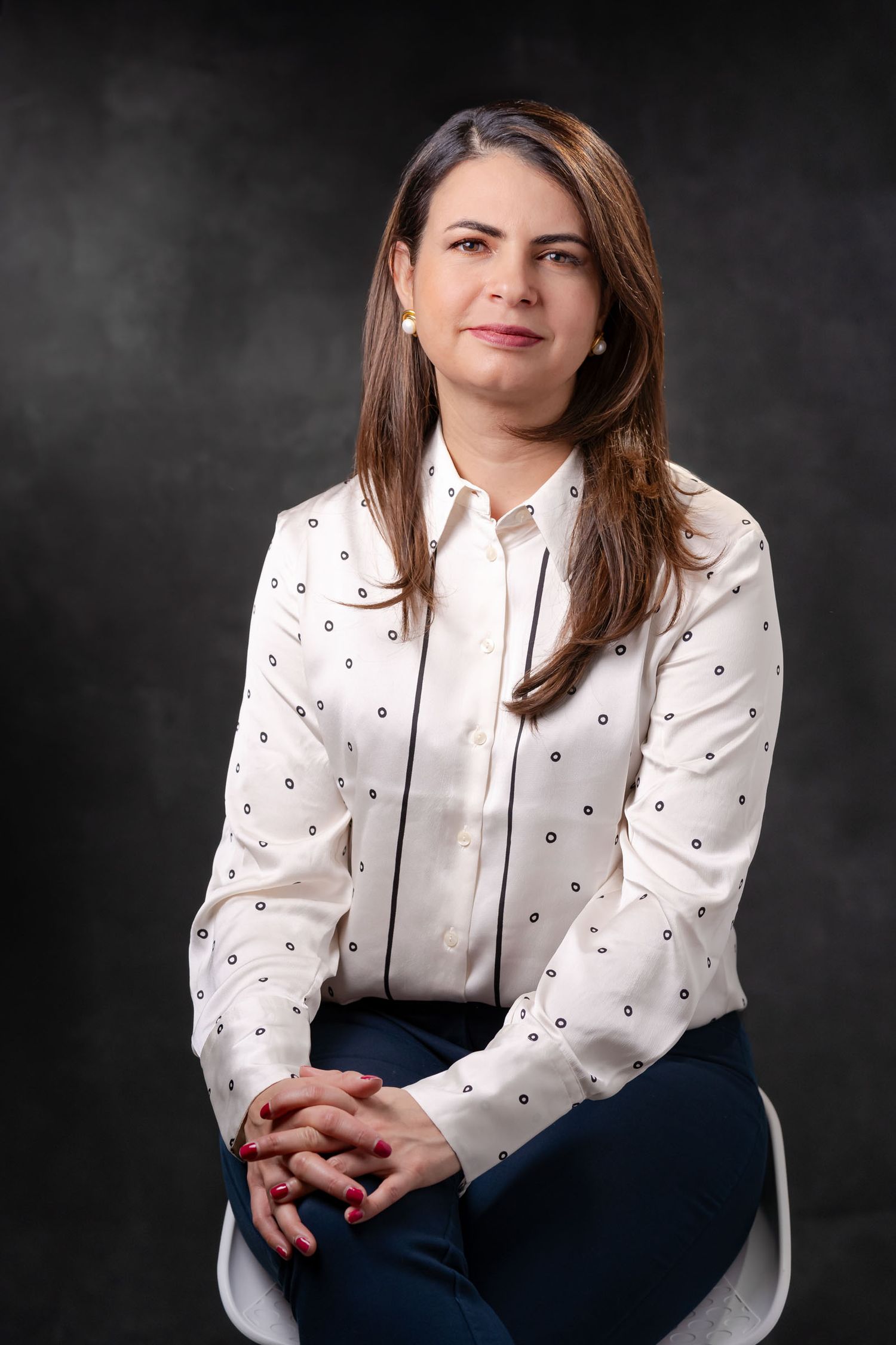 Retrato profesional y corporativo de Adriana sentada, en un fondo oscuro