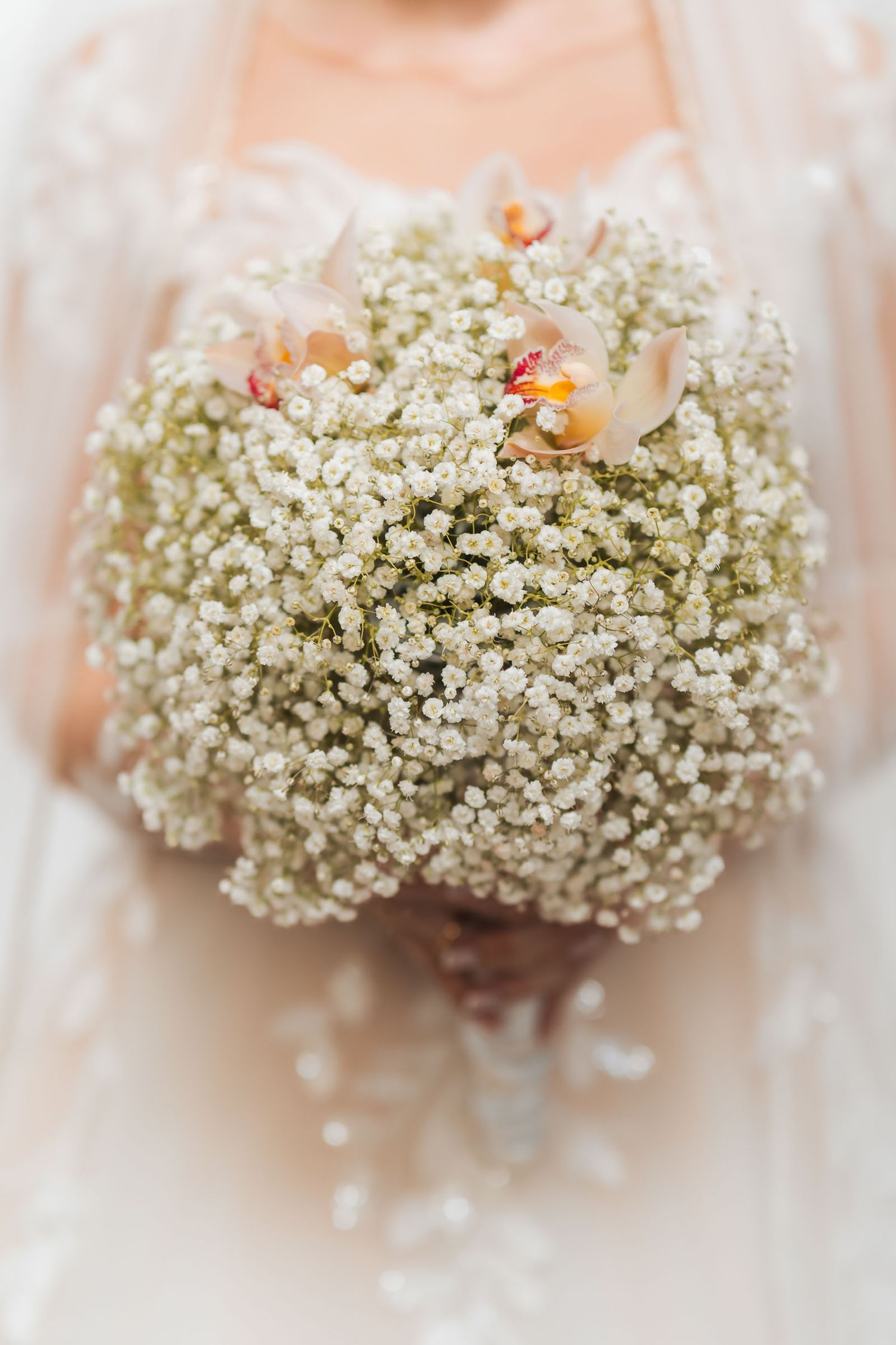 Detalle cercano: Ramo de novia redondo con abundante gypsophila y toques de color, sostenido por la novia. Boda.