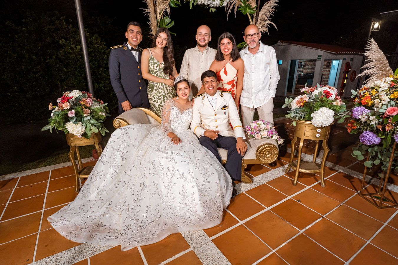 Recién casados en el centro de un sonriente grupo de amigos y familiares en su boda