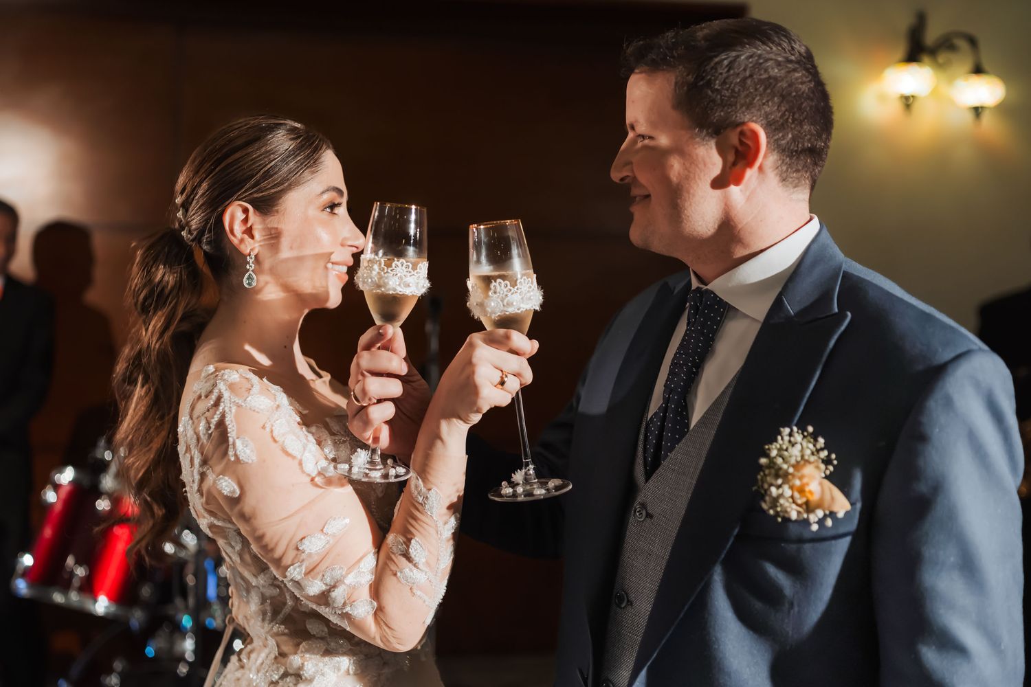 Novios hacen un brindis con copas de champagne, mirándose y sonriendo en su celebración de boda.