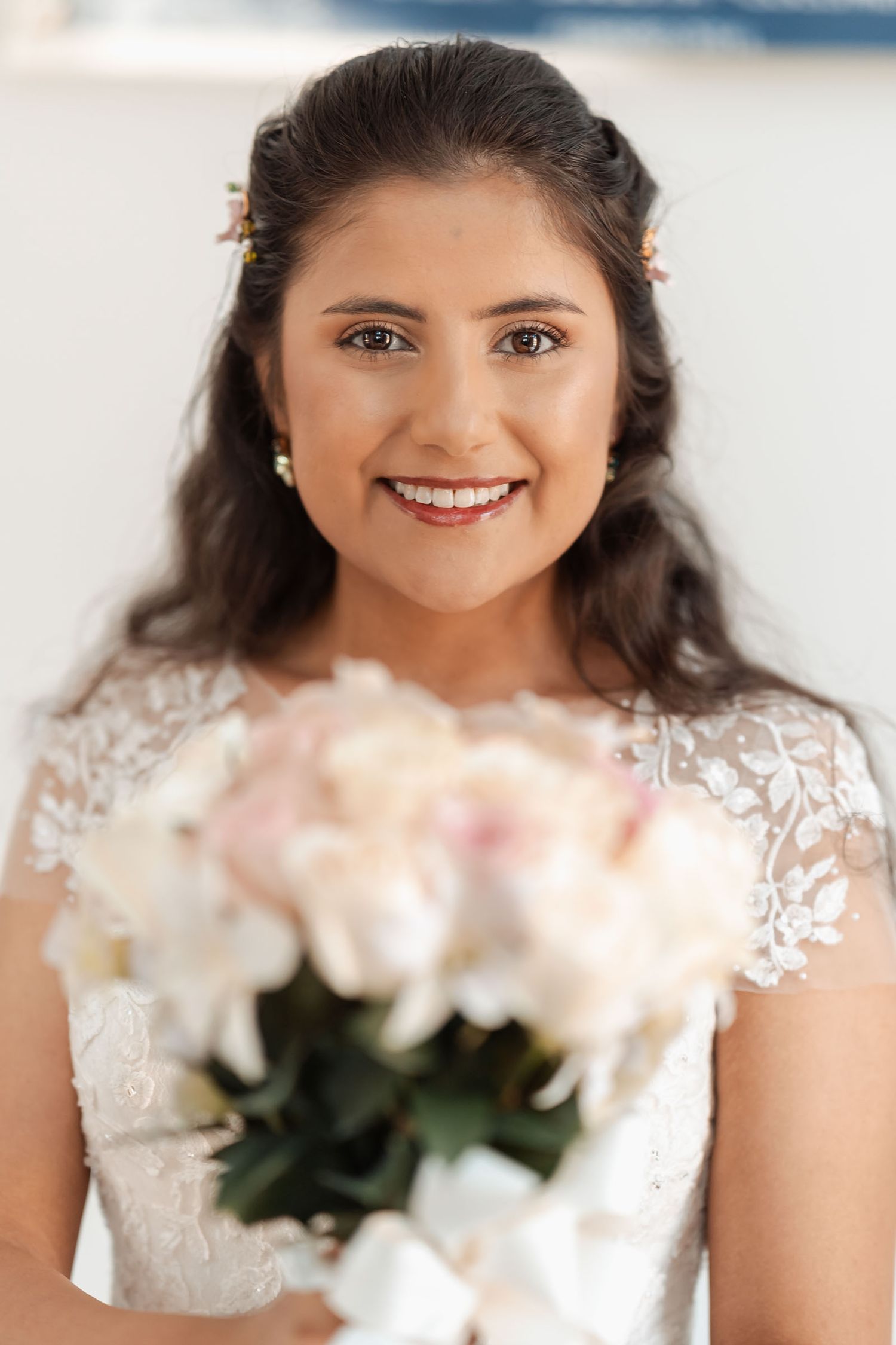 Novia sonriente con ramo de flores blancas y rosas mirando a la cámara