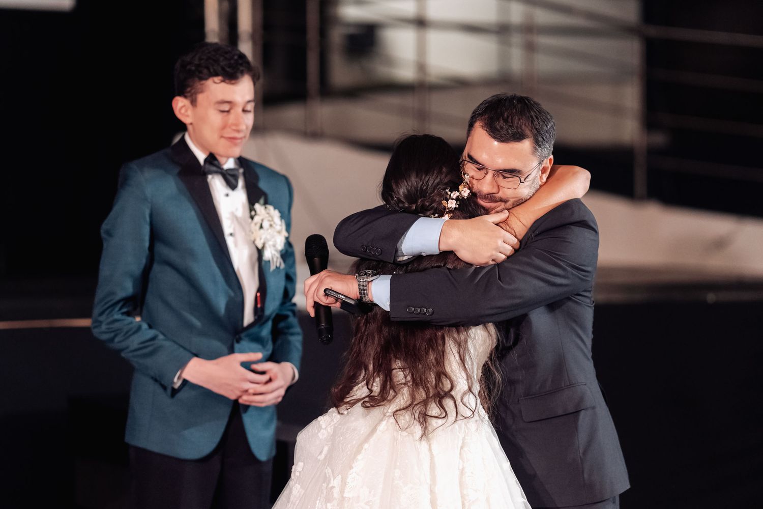 Novio comparte abrazo emotivo con familiar cercano en recepción de boda.