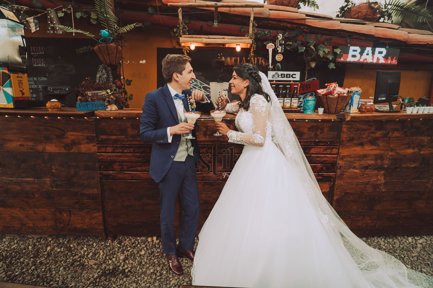 Novios brindando con champán en la barra rústica de su boda.