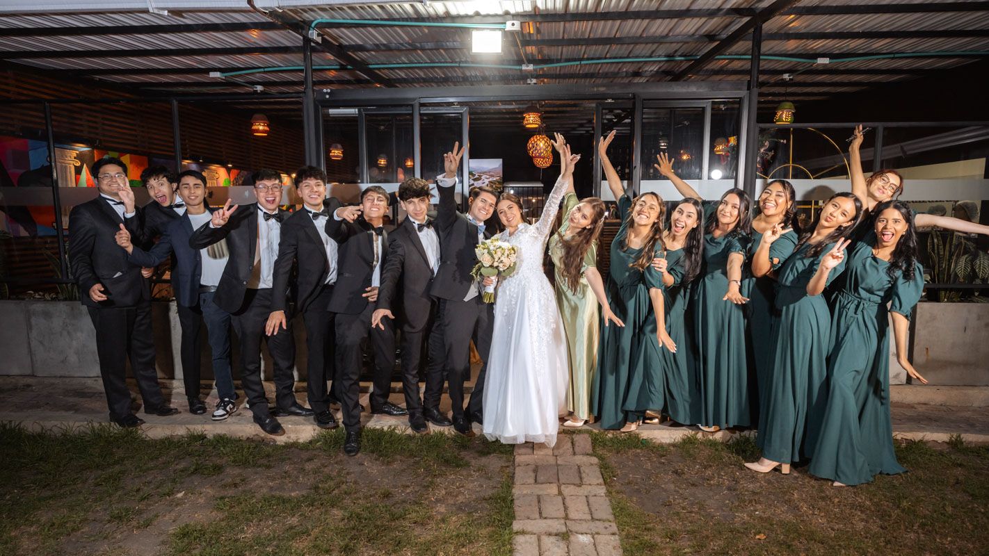 Cortejo nupcial posa feliz en exterior de noche. Novios, damas y caballeros de honor celebran juntos en boda.
