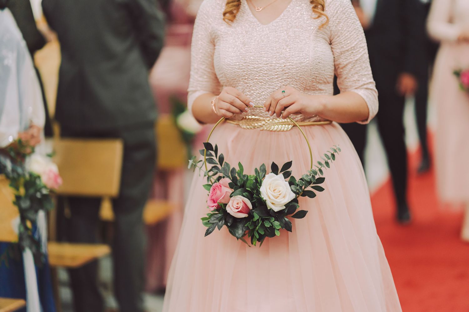 Dama de honor con vestido rosado sosteniendo un ramo de aro floral.