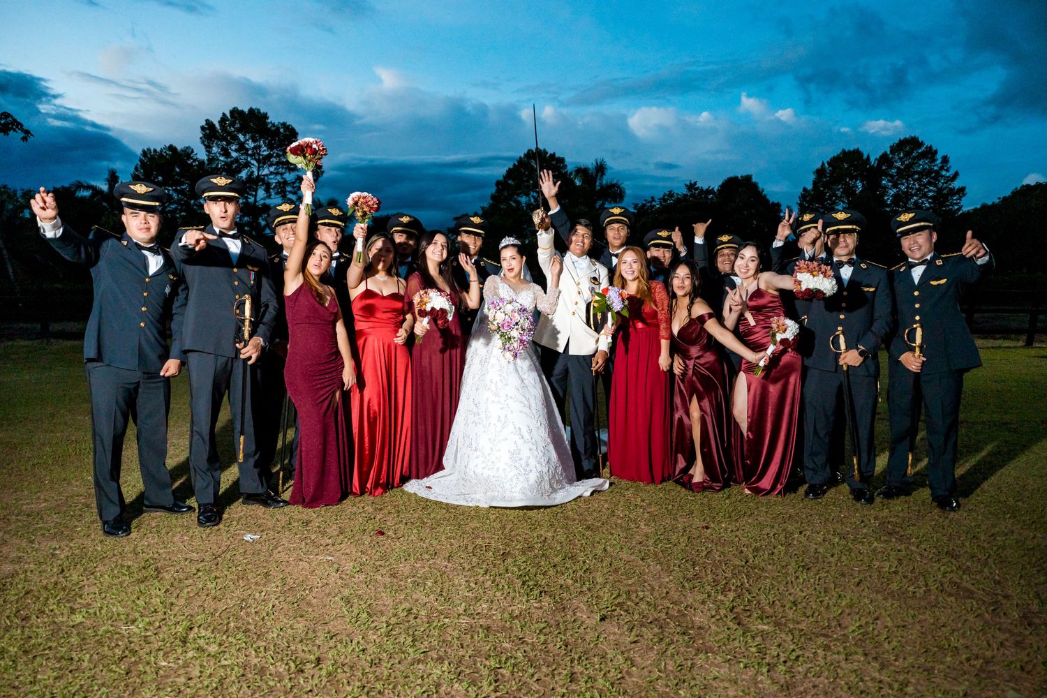 El cortejo nupcial completo, con novios, damas de honor y padrinos, posa al aire libre.