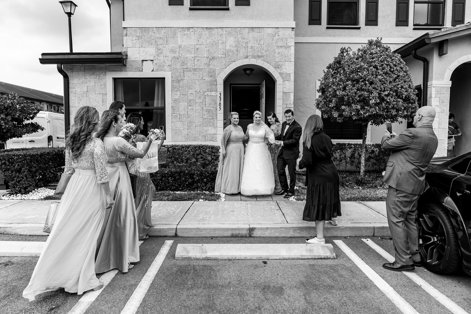 Foto B&W: Cortejo nupcial (novios, damas) posa para foto frente a edificio; fotógrafo aficionado. Boda Miami.