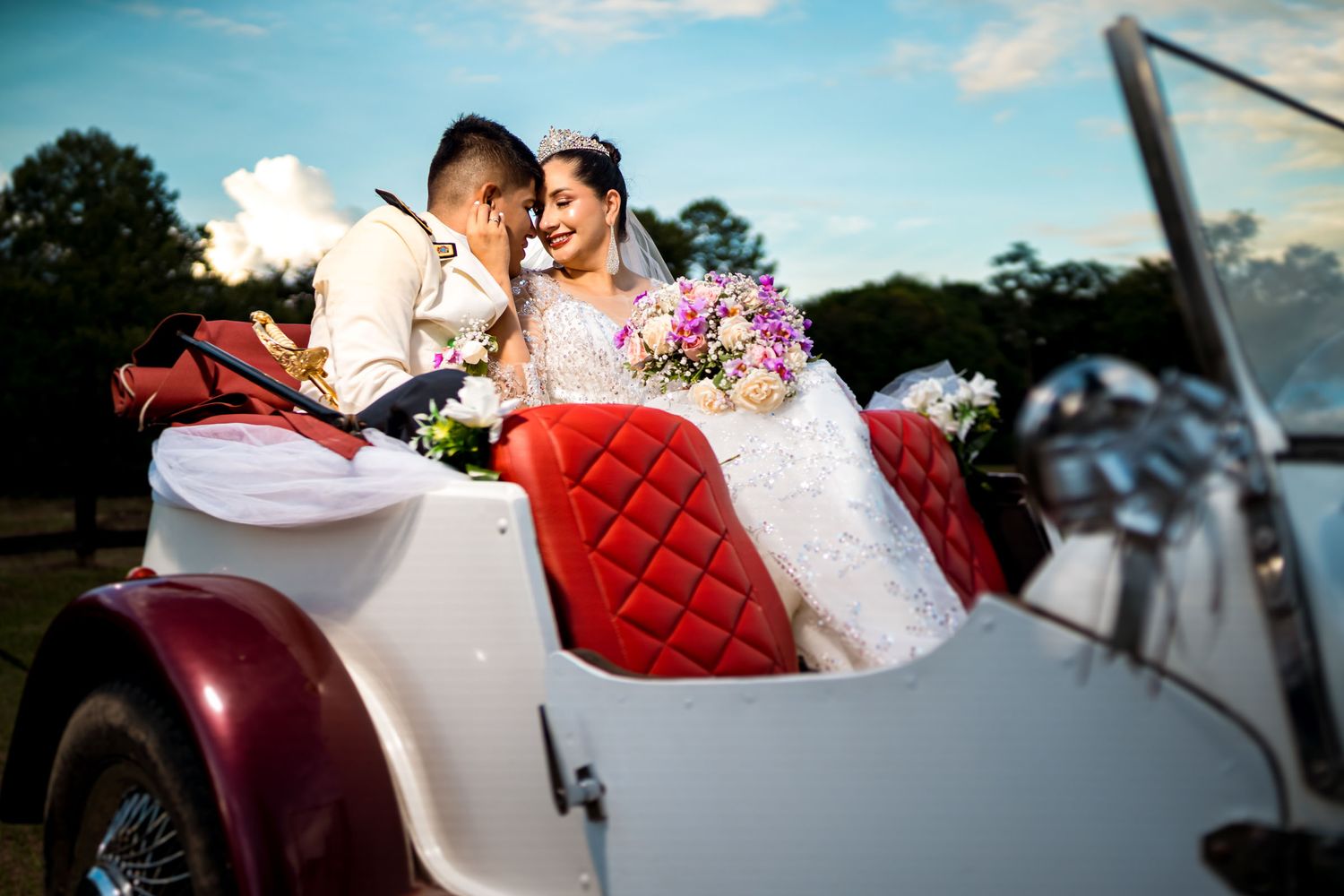 Novios recién casados sentados en la parte trasera de un carro clásico convertible decorado para la boda