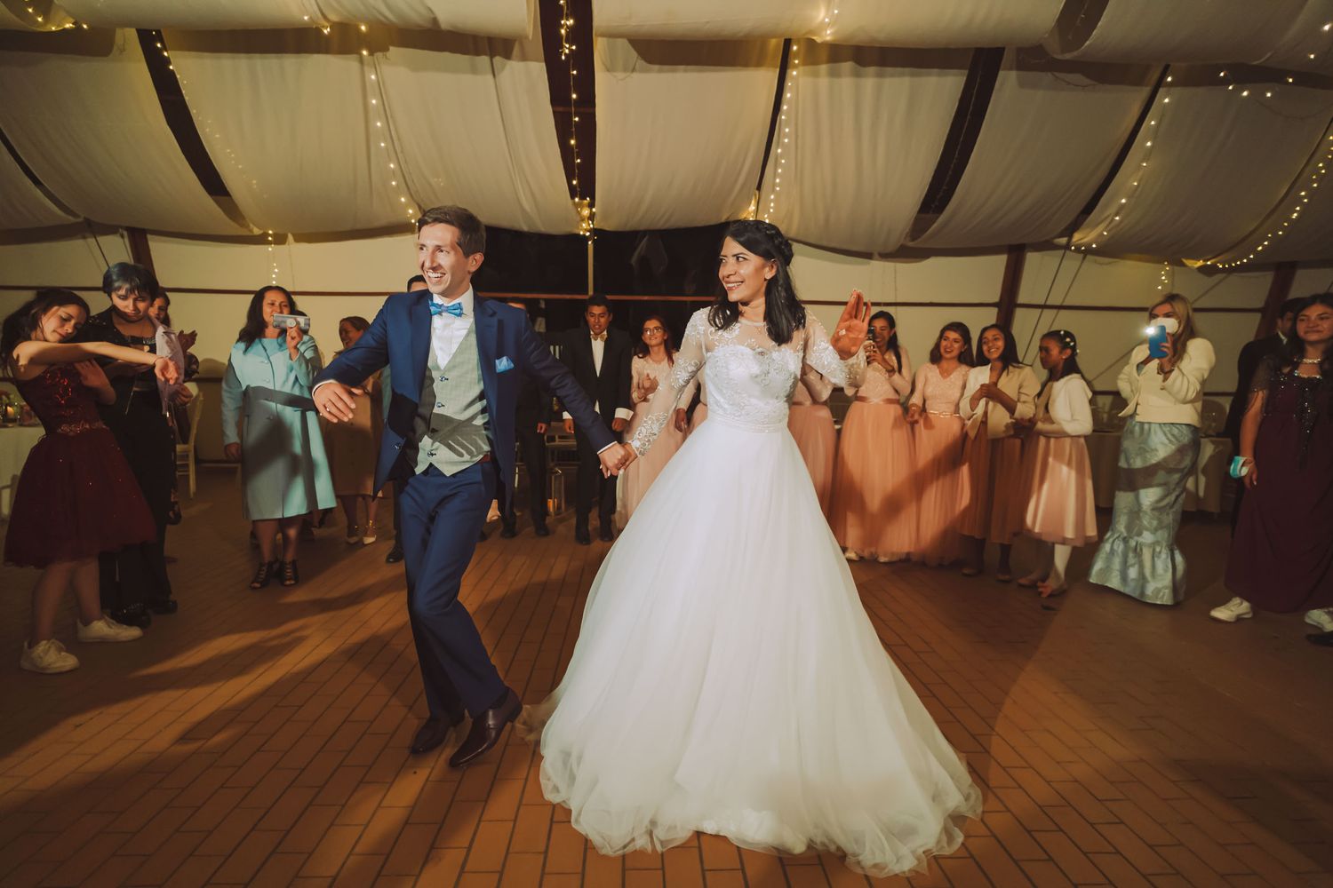 Novios bailando felices rodeados de invitados en la fiesta de su boda