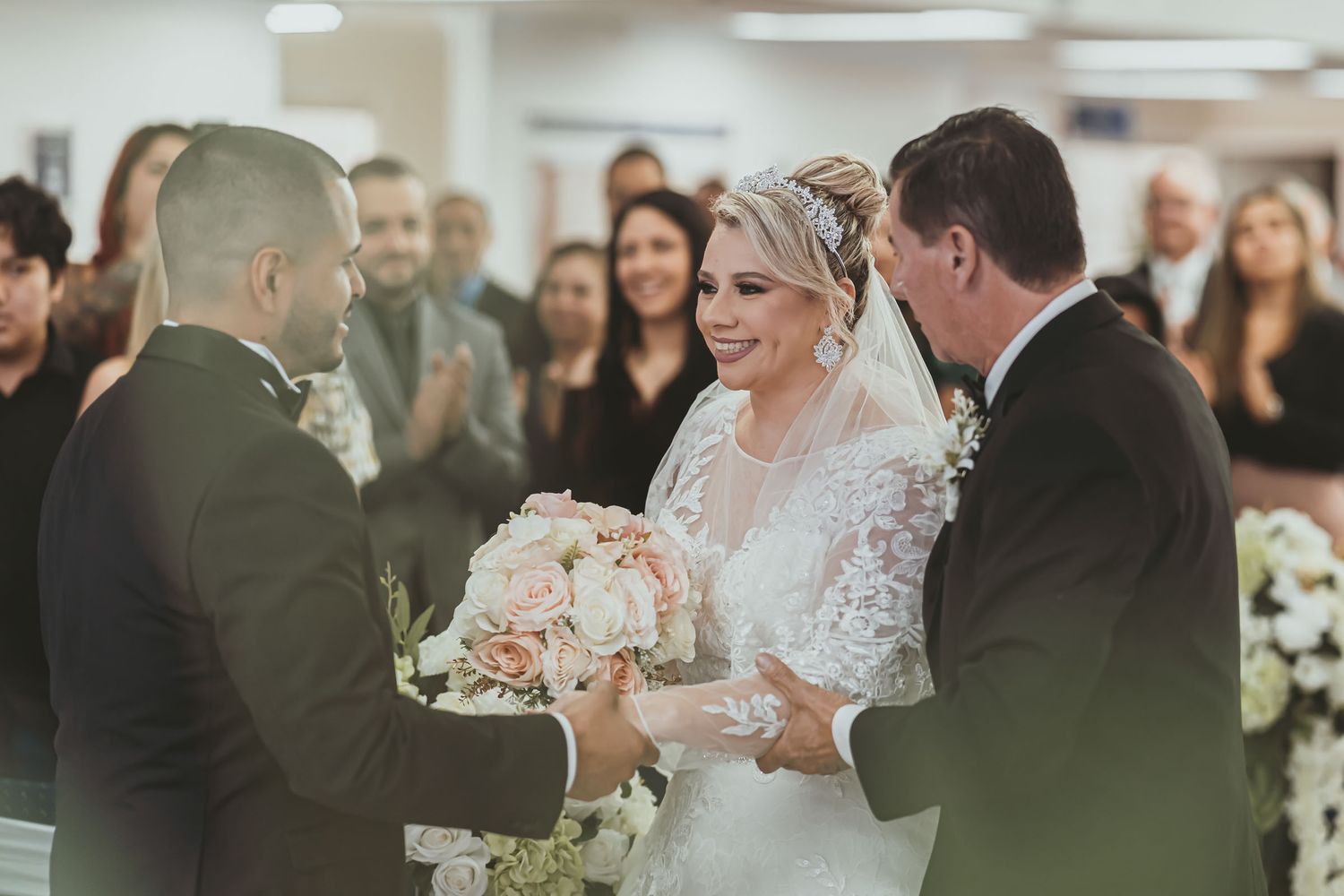 Padre entrega mano de novia radiante al novio en altar; momento emotivo ceremonia boda, invitados fondo.