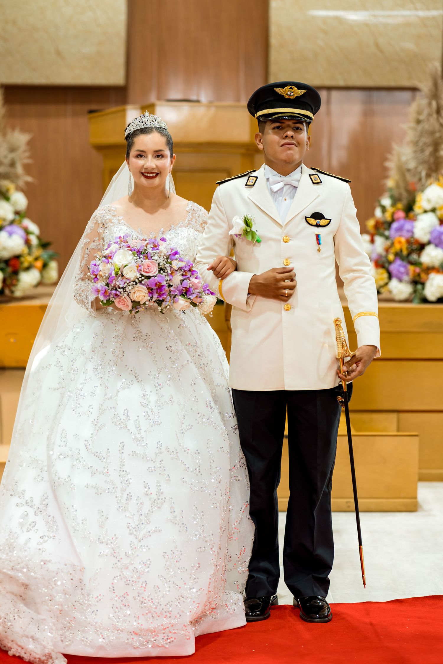 Novios caminan por el pasillo rojo durante la ceremonia de su boda