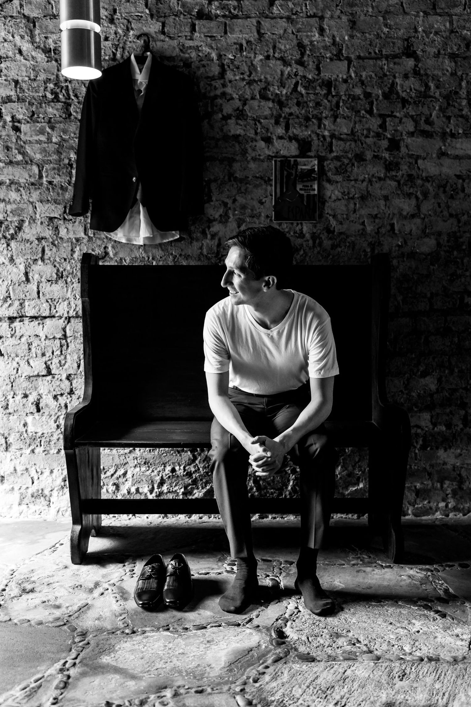 Novio atándose los zapatos en una habitación rústica, foto en blanco y negro.