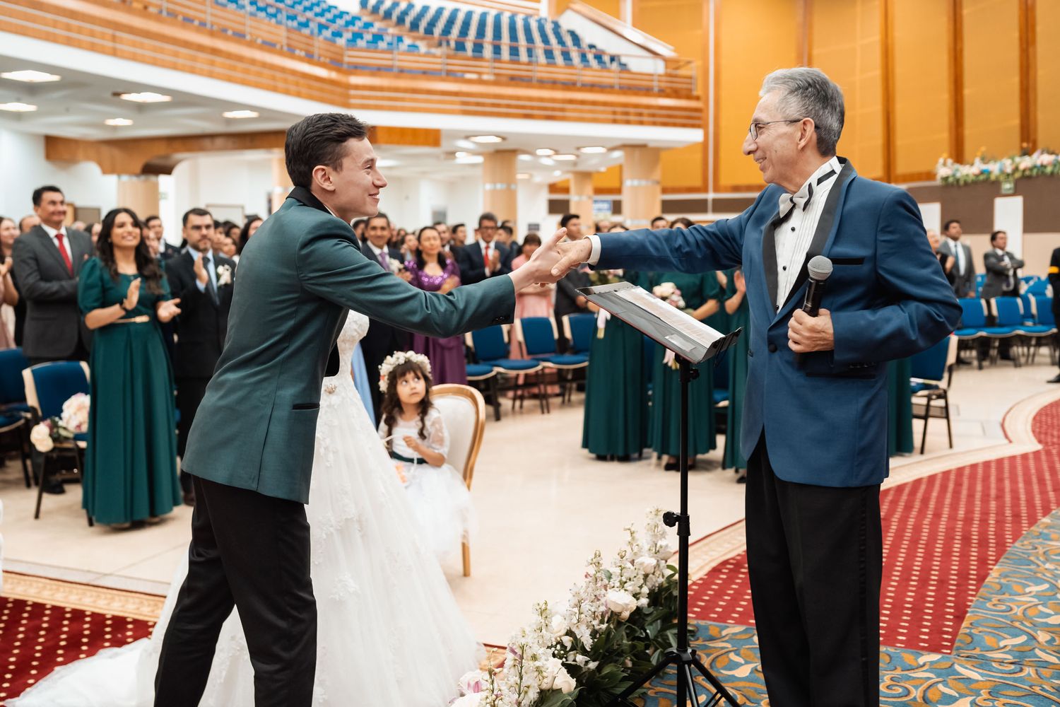 Novio saludar a oficiante de boda mientras los intivados aplauden
