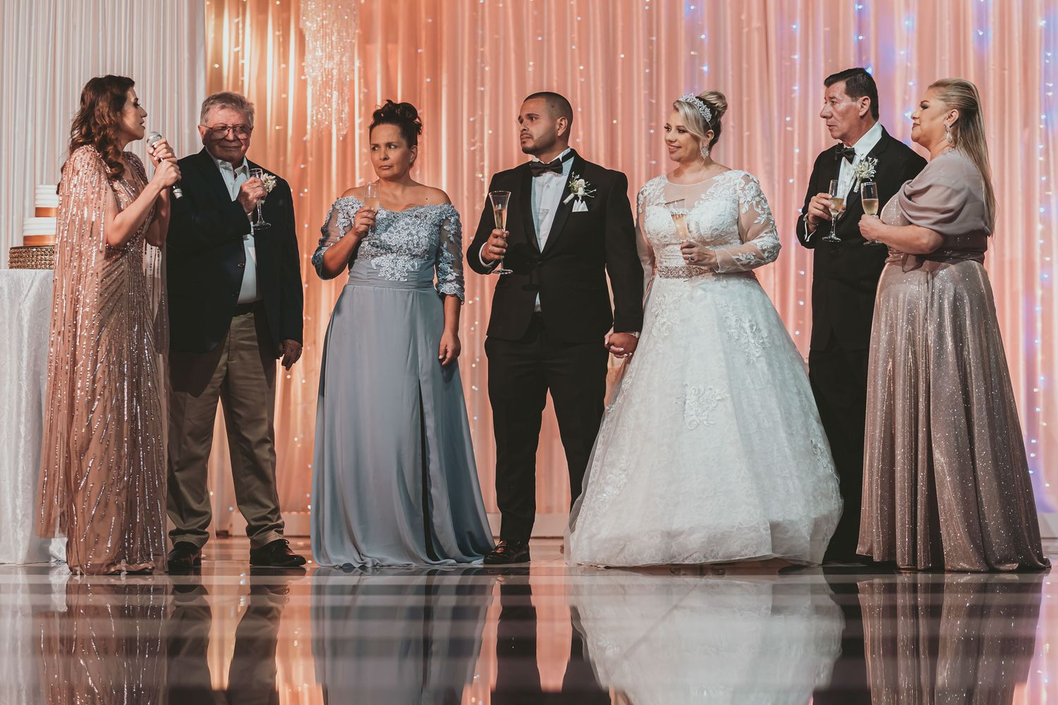 Novios y familiares (padres?) de pie escuchan atentos durante brindis o discurso en recepción de boda.