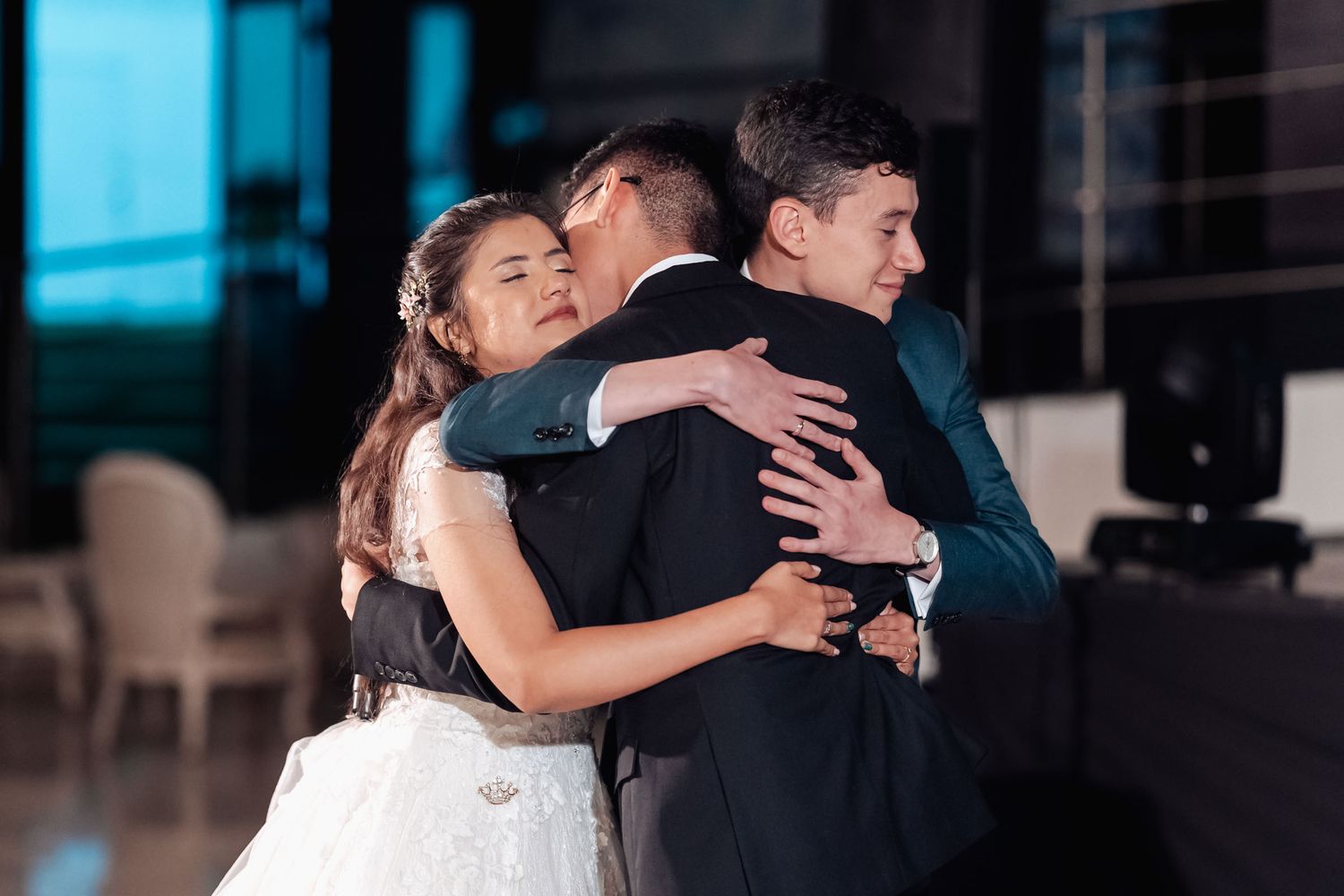 Novio en abrazo grupal afectuoso con la novia y un invitado en boda