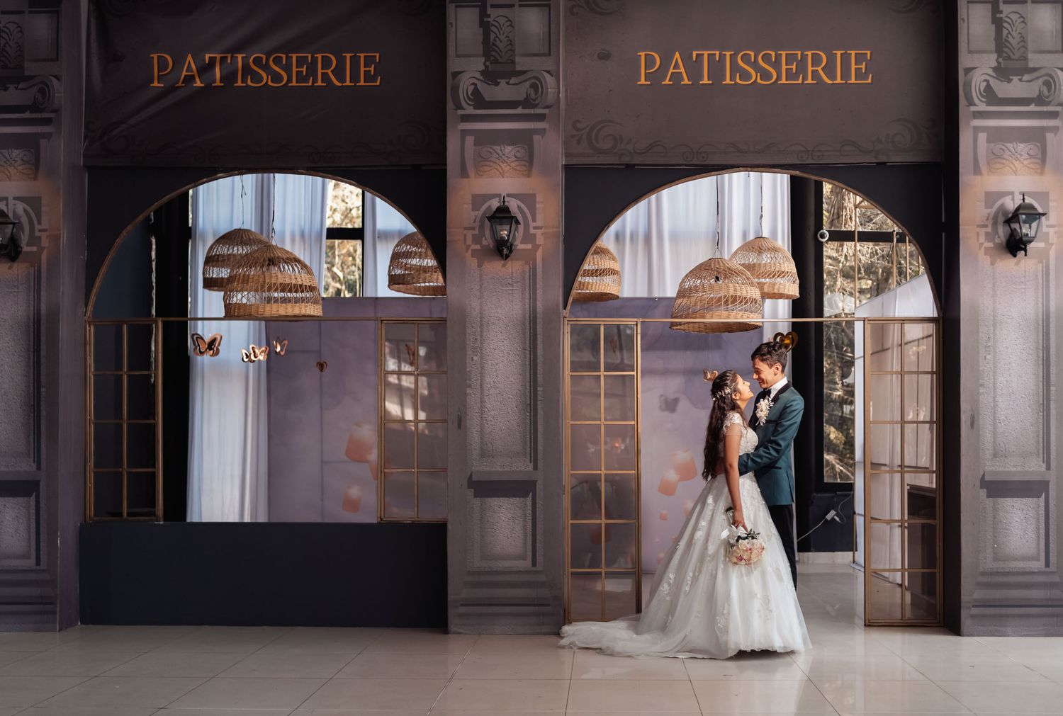 Novios elegantes frente a fachada de pastelería con encanto urbano
