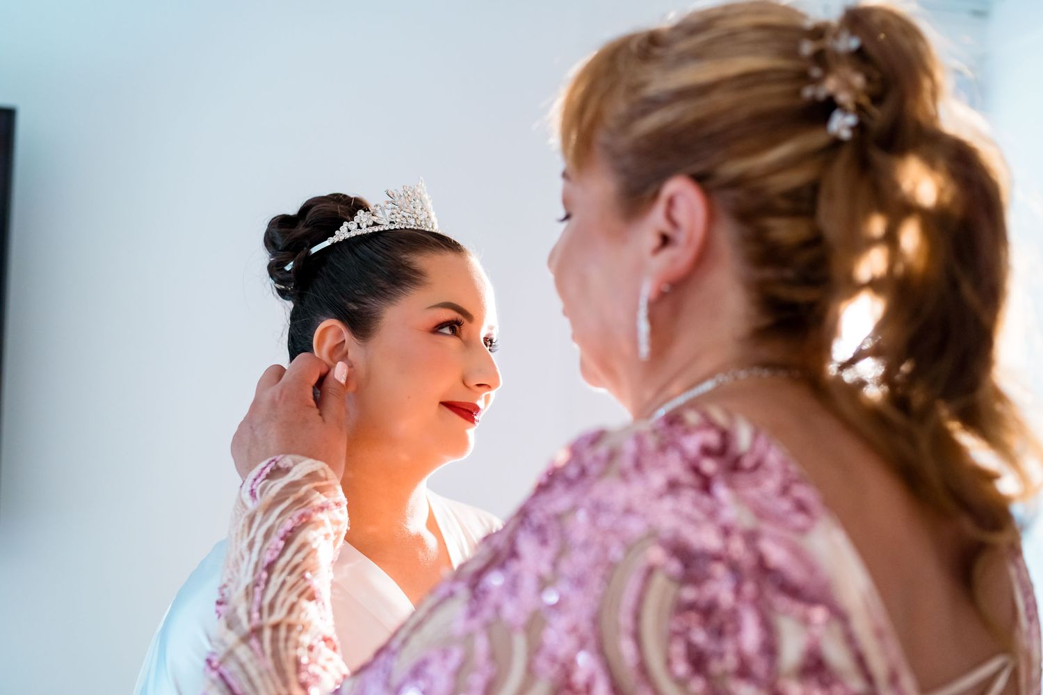 La madre de la novia le ayuda a ponerse los aretes durante los preparativos de la boda