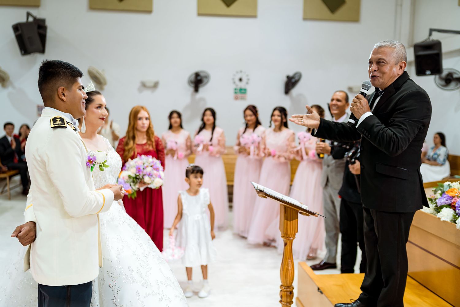 Vista de la ceremonia de boda con el pastor, los novios y las damas de honor en el altar