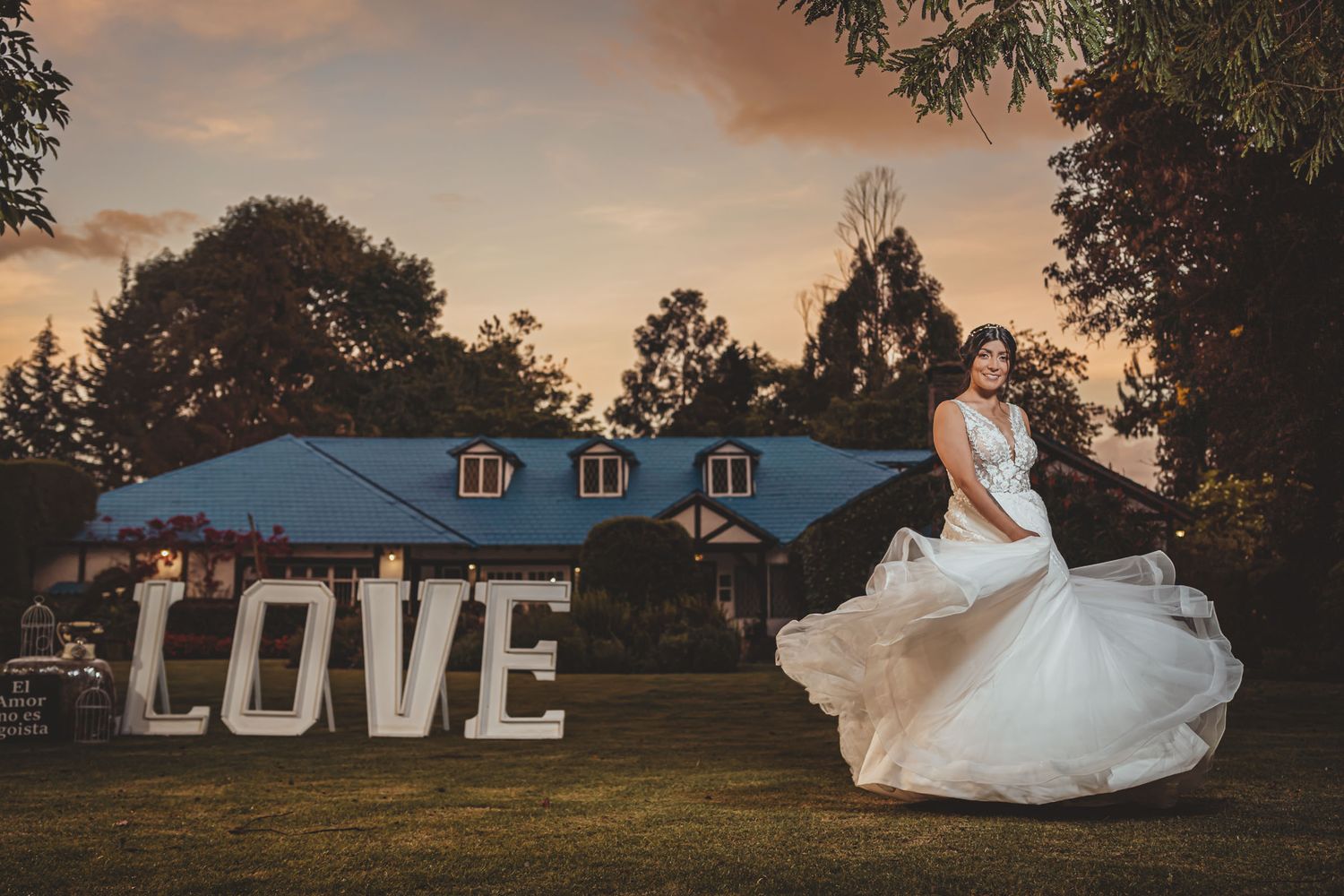 Novia gira feliz con vestido blanco en jardín frente a letras gigantes 