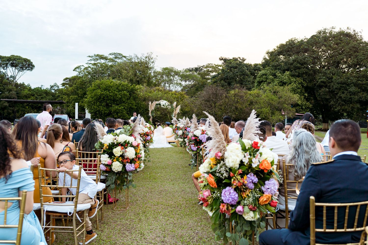 Vista desde el fondo del pasillo de la ceremonia, mostrando a los invitados y la decoración floral