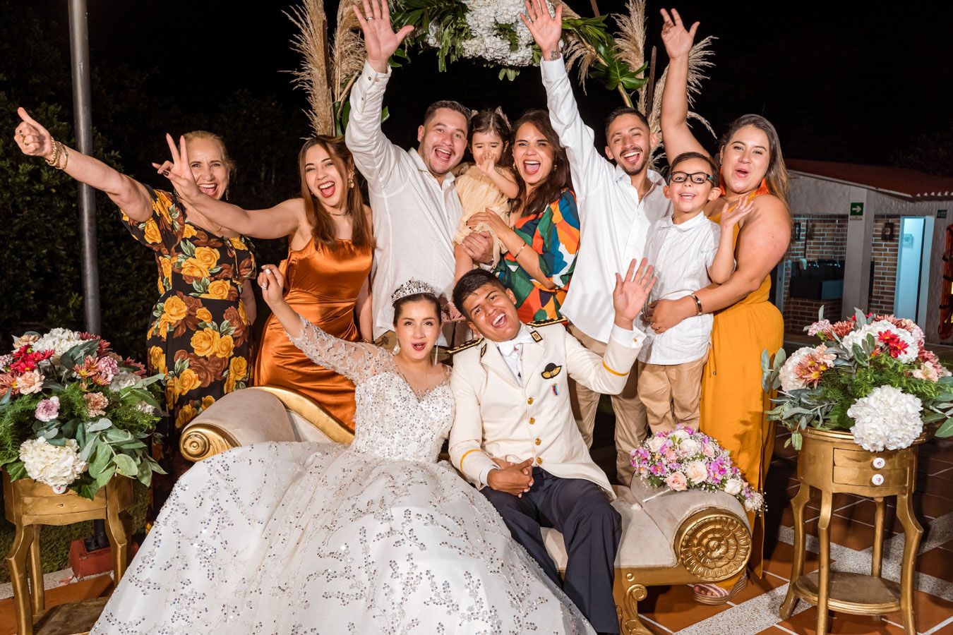 Invitados celebran con los brazos arriba junto a los novios en una animada foto grupal de la boda