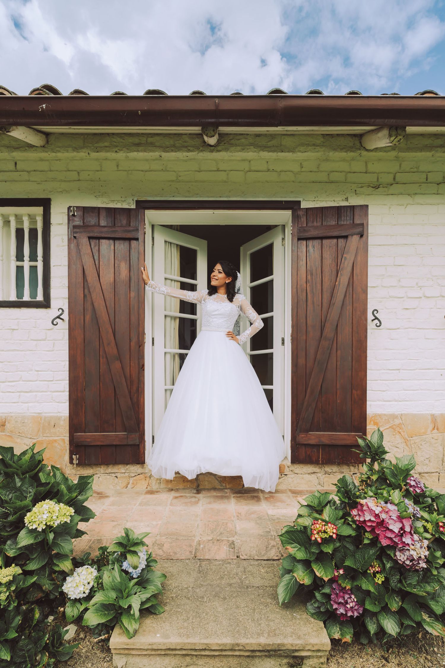 Novia en el umbral de una puerta de madera en una casa rústica.