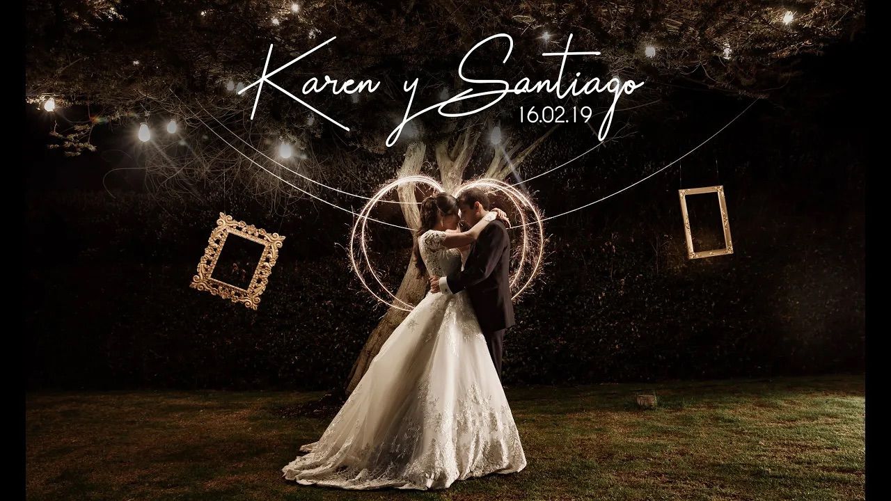 Novios se abrazan bajo un corazón de luces en la noche exterior, con marcos decorativos. Foto de boda romántica.