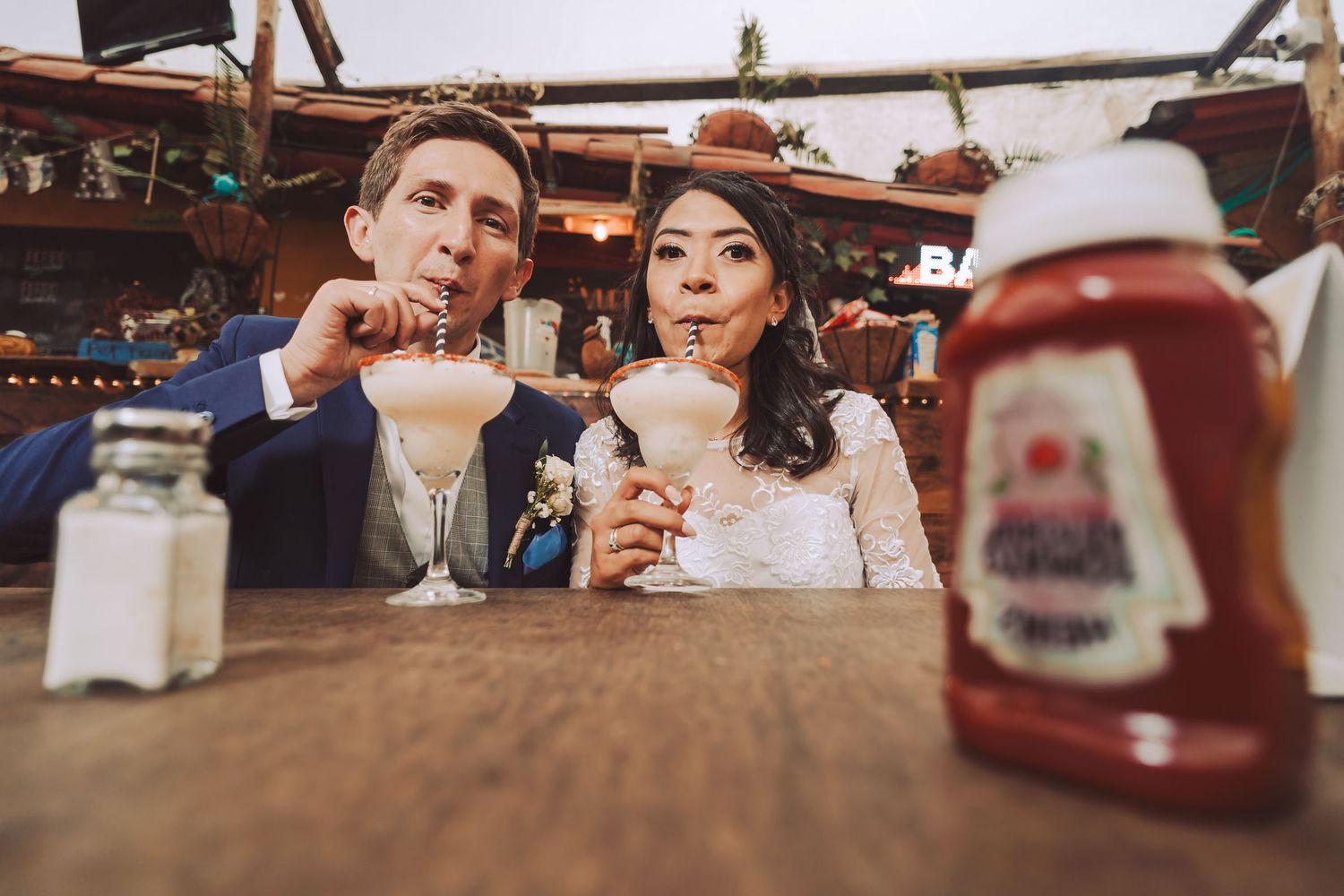 Novios bebiendo malteadas en una cafetería durante su sesión de fotos de boda.