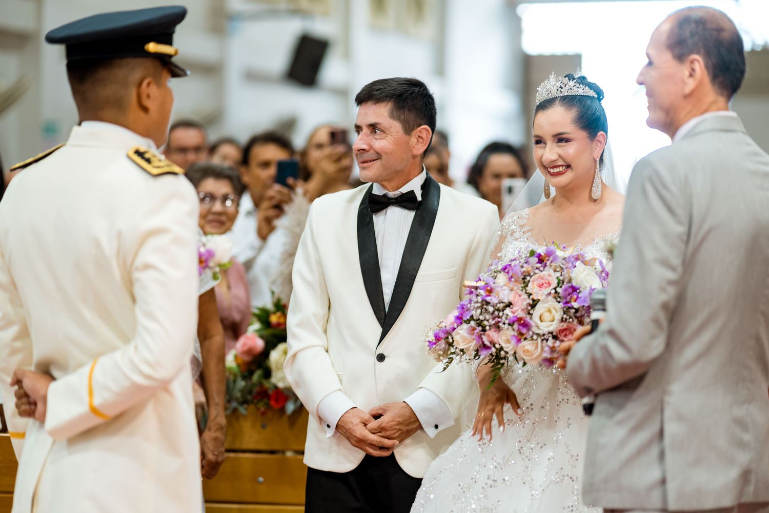El novio reciba a la novia mientras su padre la entrega en el altar