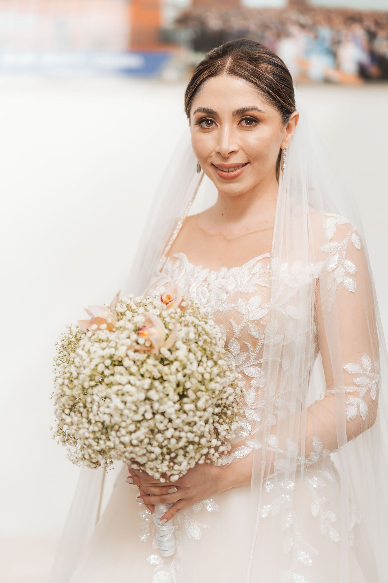 Retrato novia sonriente con vestido bordado manga larga, velo y gran ramo (gypsophila). Fotografía boda.
