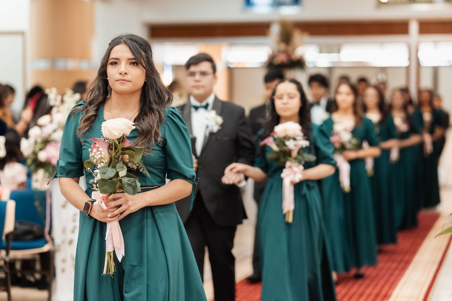 Damas de honor con vestidos teal caminando en procesión por pasillo de iglesia