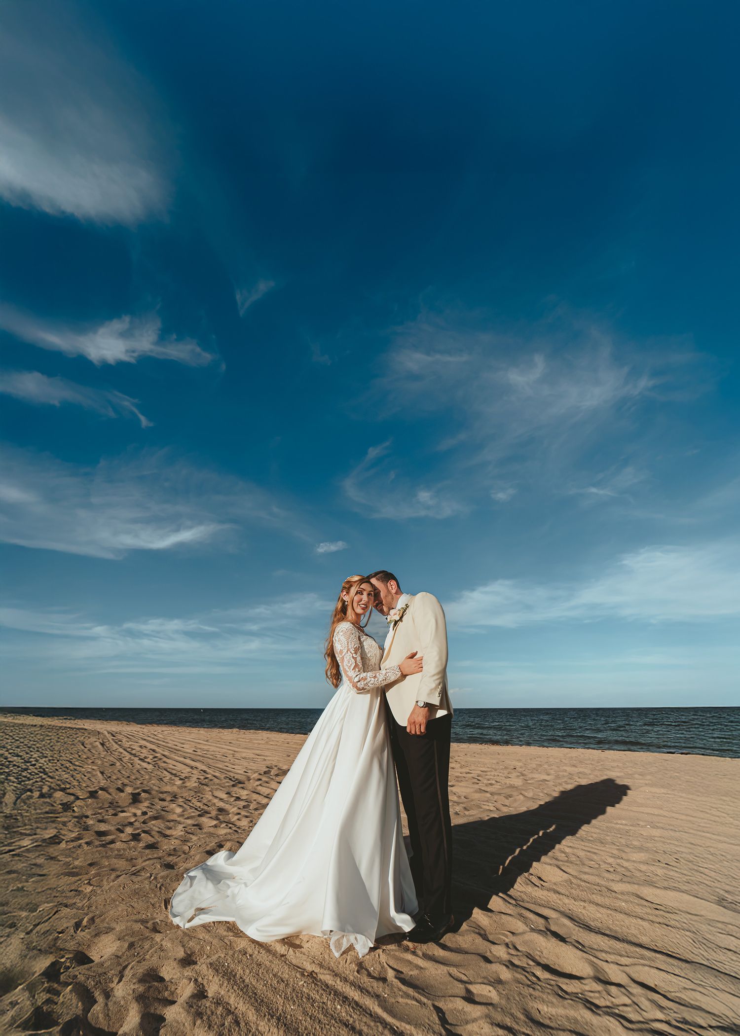 Novios se besan apasionadamente en la playa con el mar de Miami y el cielo detrás. Foto de boda romántica.
