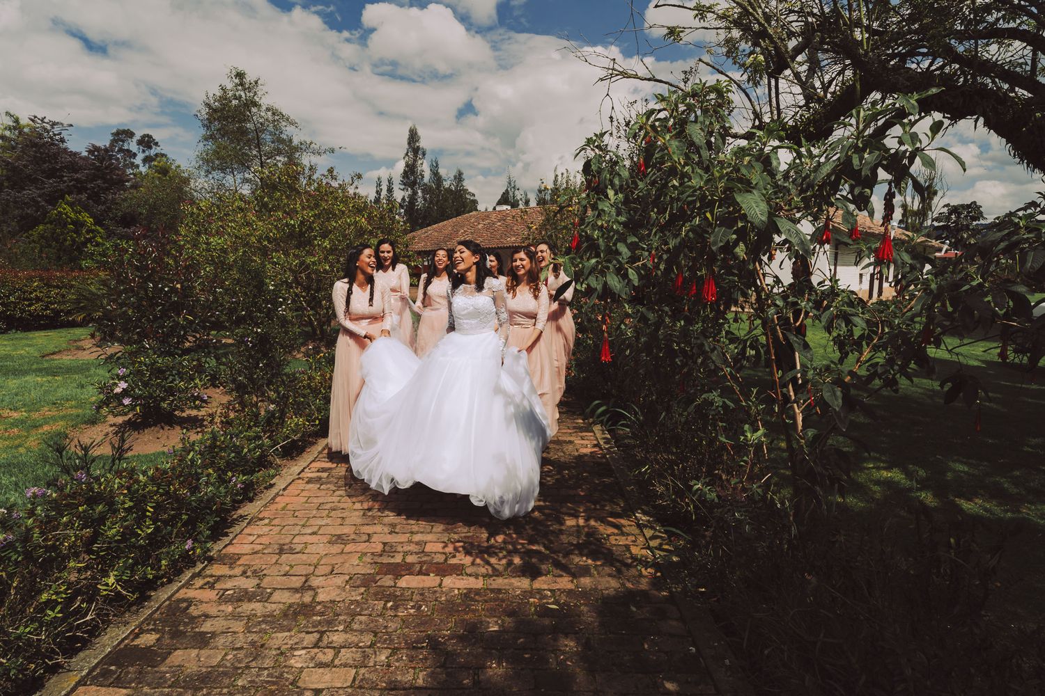 Novia caminando con sus damas de honor en un sendero de jardín en Cajicá.