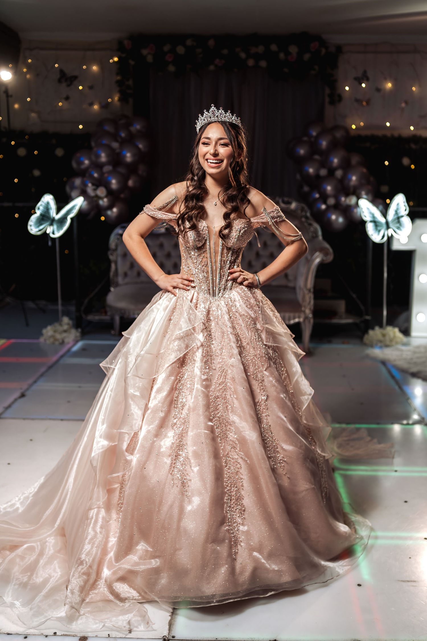 Quinceañera sentada de perfil con vestido y tiara, reflejada en espejo; fotografía artística en blanco y negro.