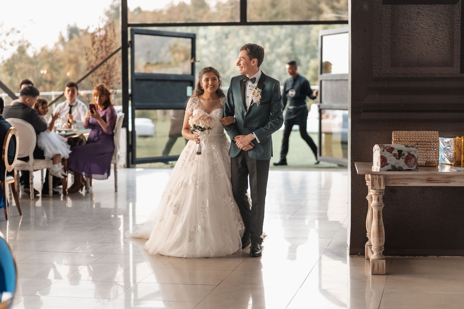 Novios sonrientes caminando de la mano en elegante salón de bodas moderno