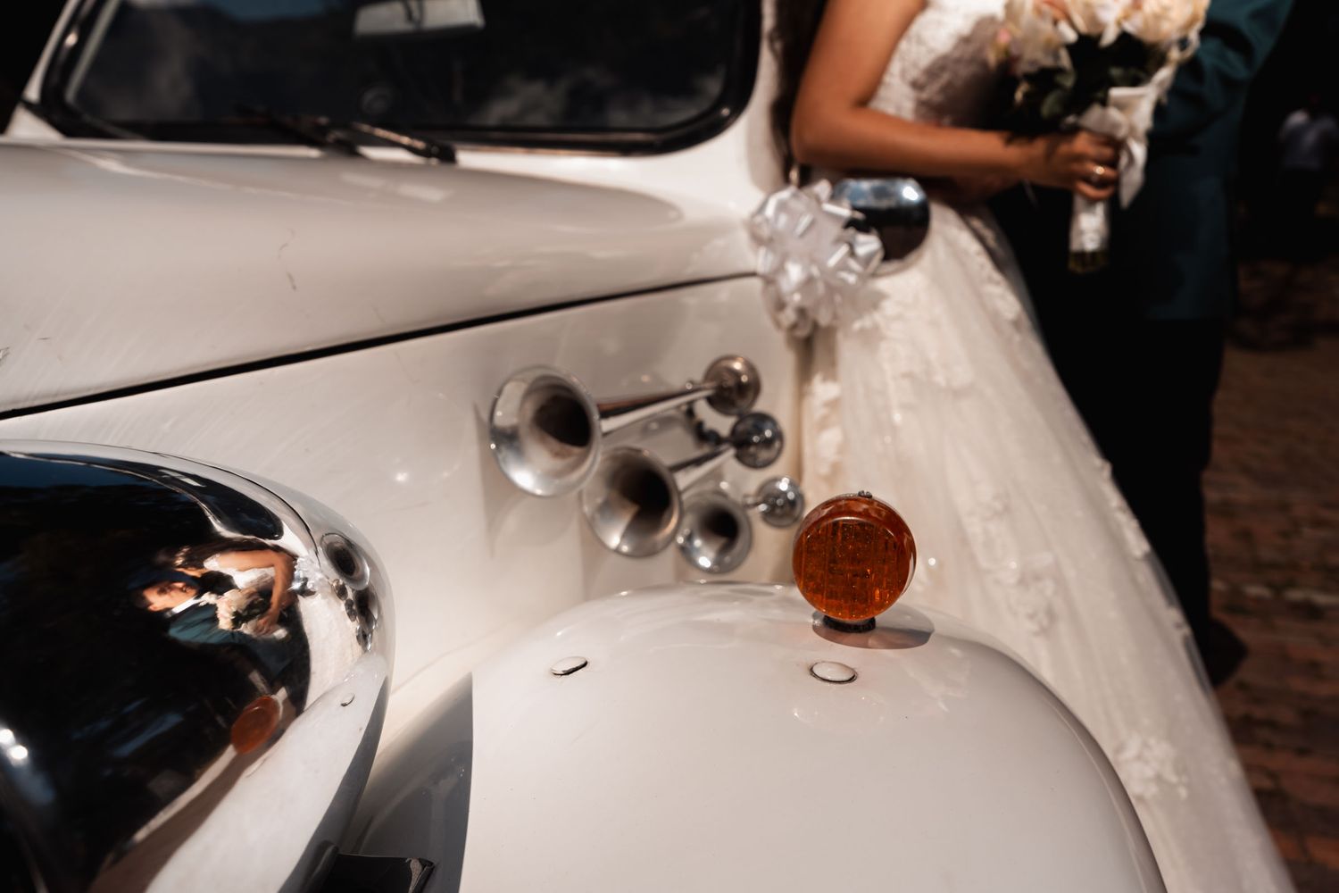 Reflejo de novios en carro clásico blanco