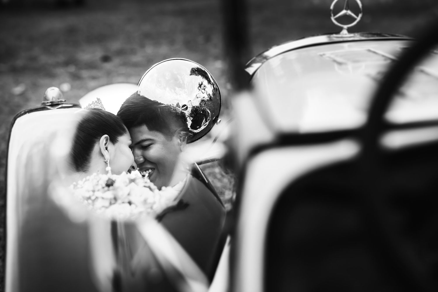 Detalle artístico en blanco y negro de los anillos de boda sobre la superficie de un carro clásico.